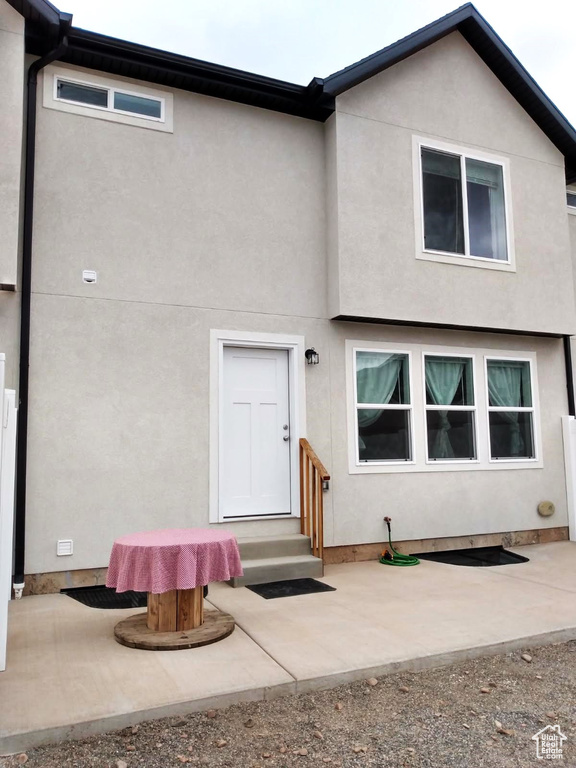 Rear view of house with stucco siding and a patio