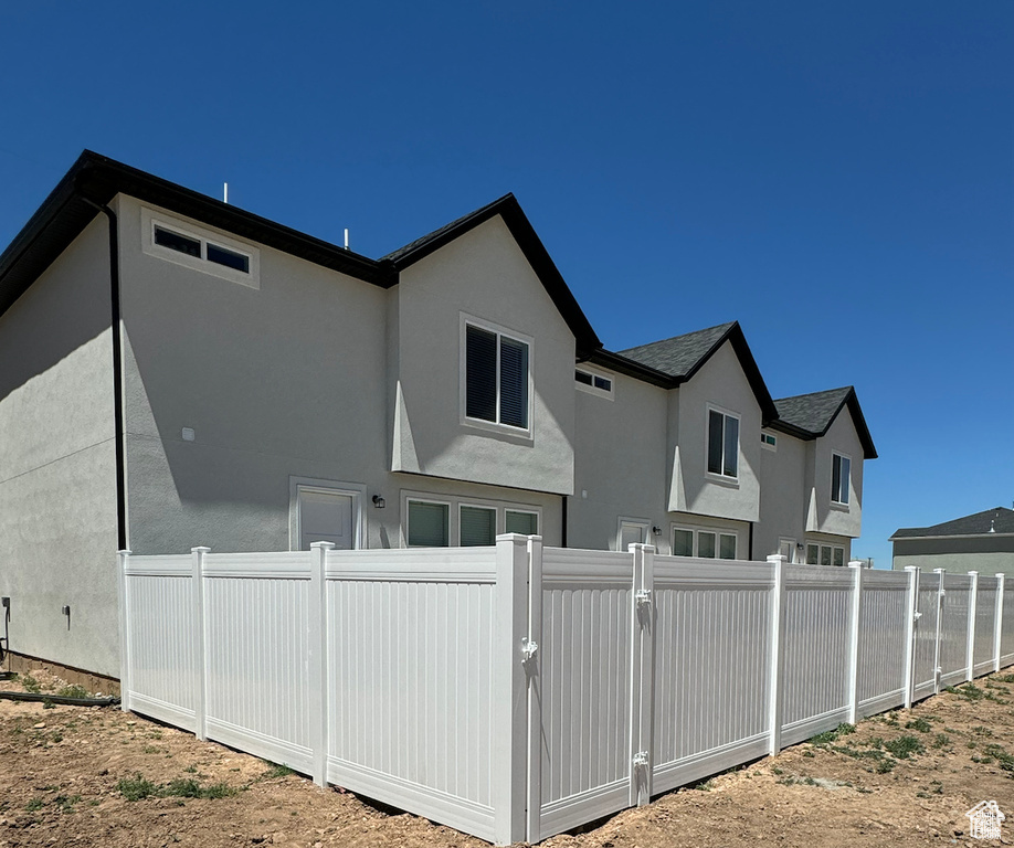 Back of property with fence, stucco siding, and a gate