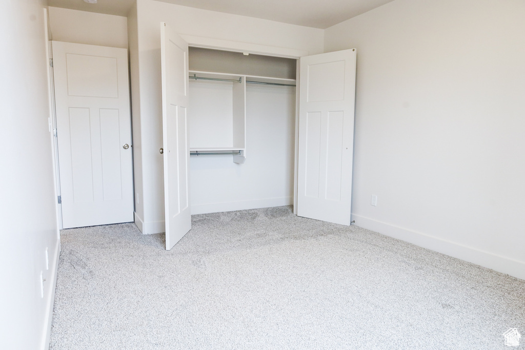Unfurnished bedroom featuring carpet, a closet, and baseboards