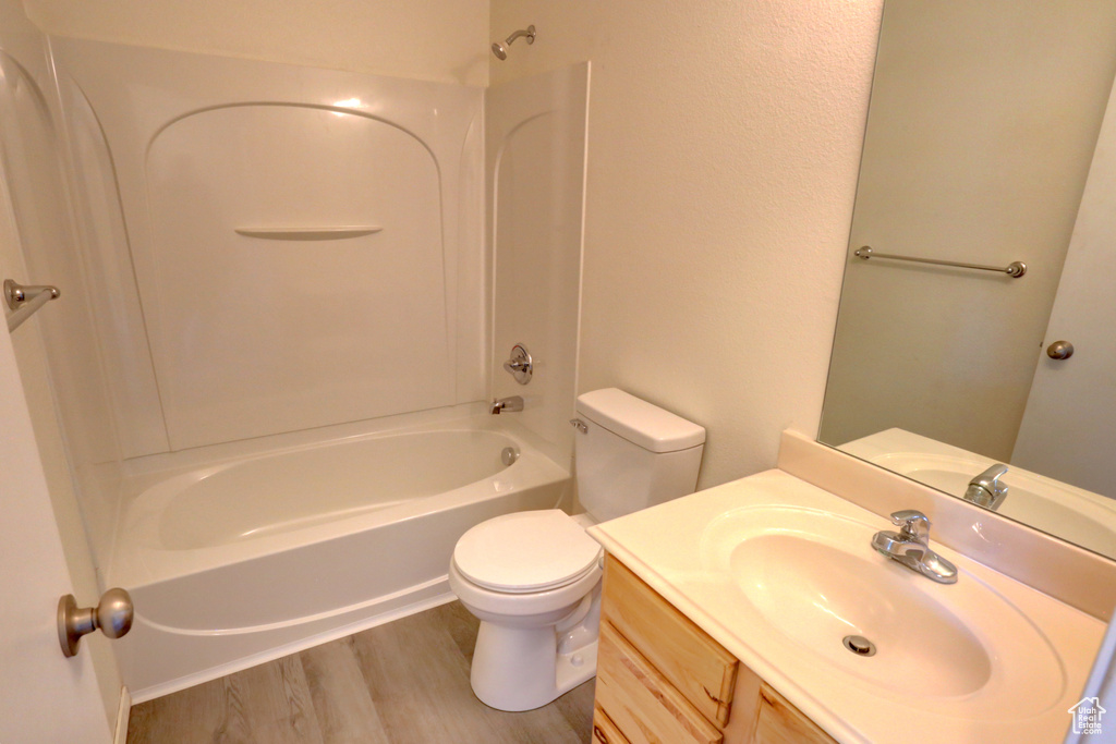 Full bathroom with toilet, wood finished floors, vanity, and shower / bathtub combination