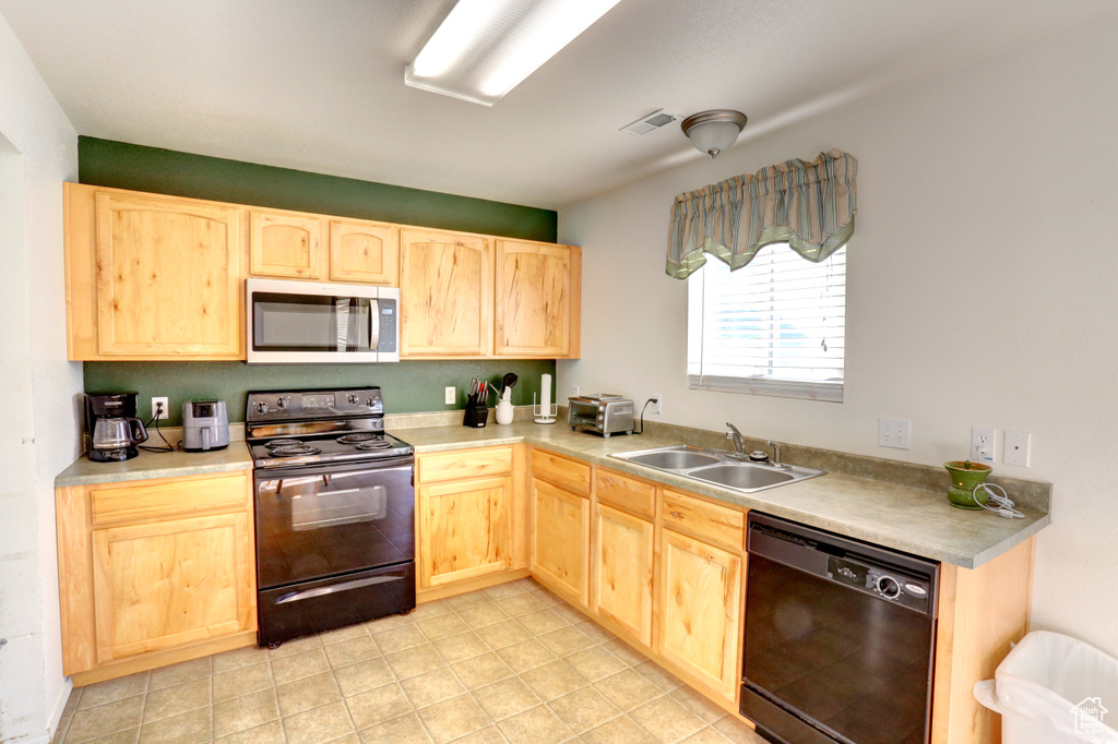 Kitchen with black appliances, light brown cabinetry, a sink, light countertops, and light tile patterned floors