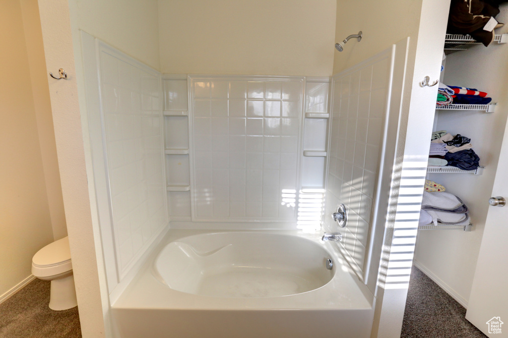 Bathroom featuring toilet, shower / bath combination, and baseboards