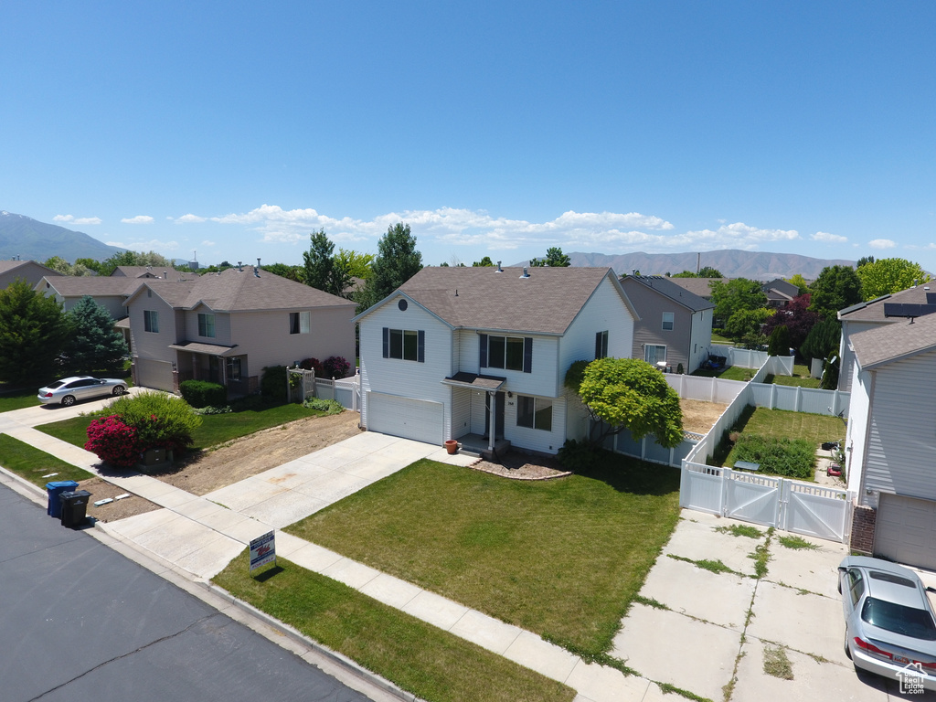 Traditional-style home with a residential view, an attached garage, a gate, driveway, and a mountain view