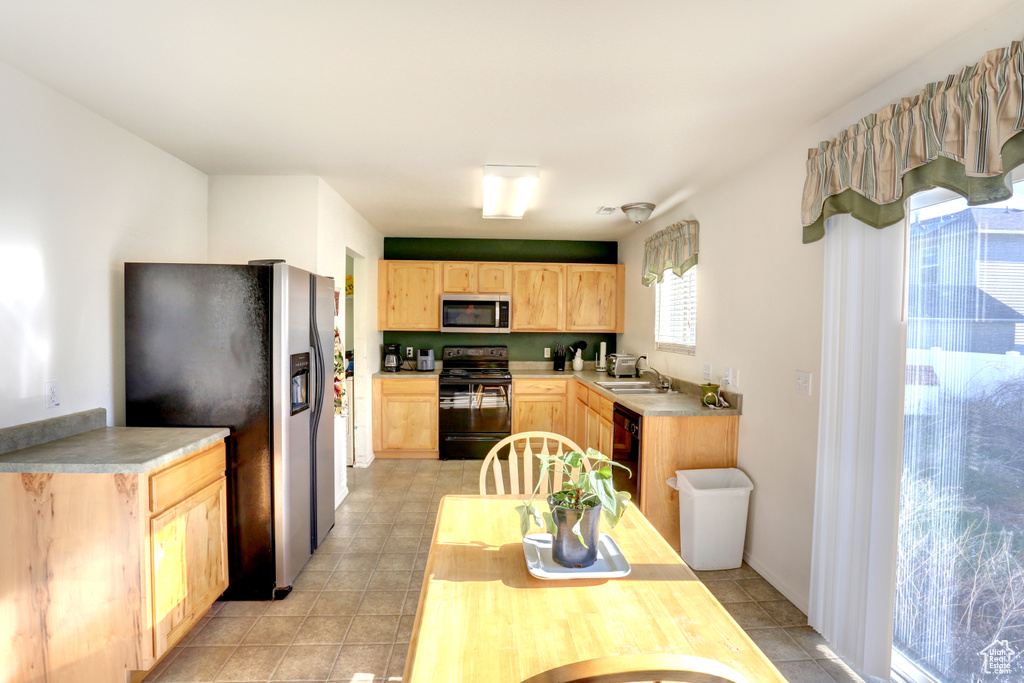 Kitchen with black appliances, light brown cabinets, light tile patterned floors, a sink, and light countertops
