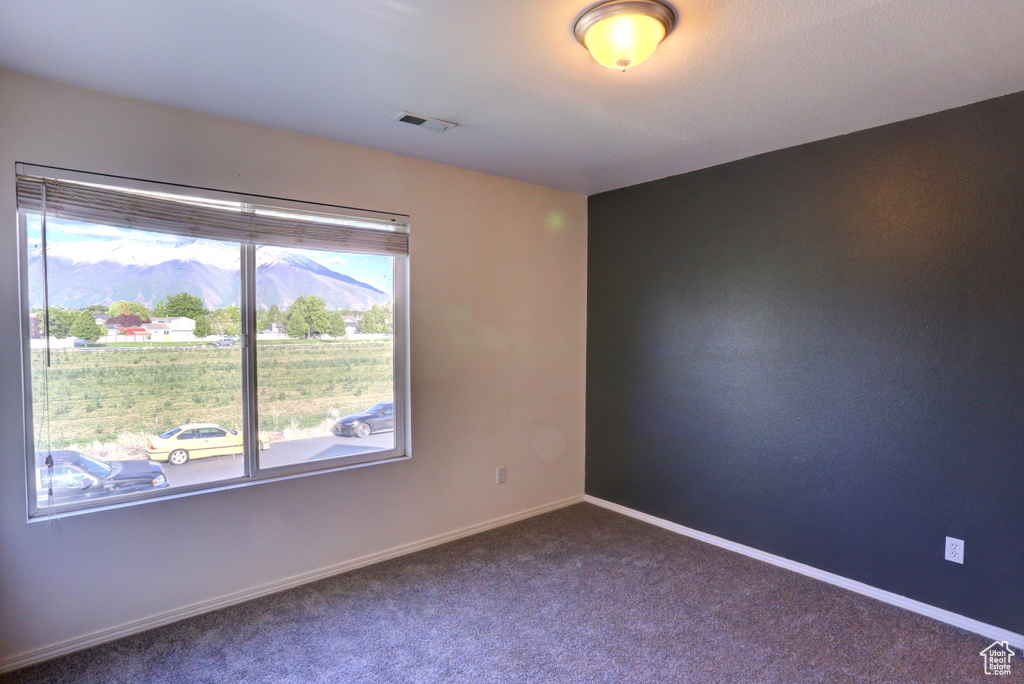 Spare room featuring dark carpet and baseboards