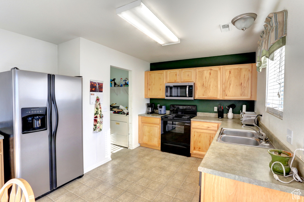 Kitchen featuring appliances with stainless steel finishes, light brown cabinets, a sink, and light countertops