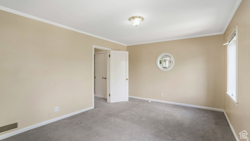 Carpeted empty room with baseboards and crown molding