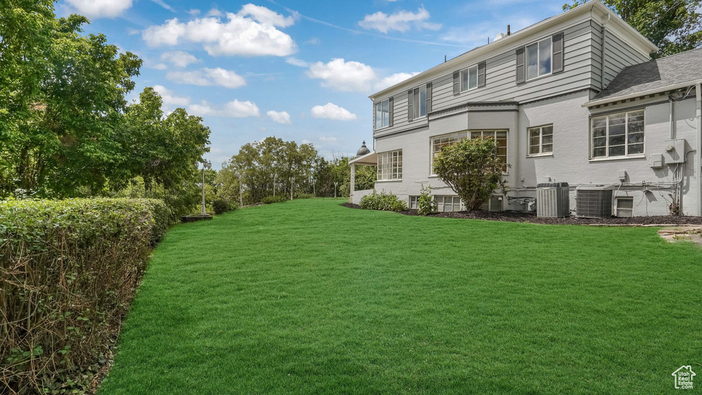 View of green lawn with central air condition unit