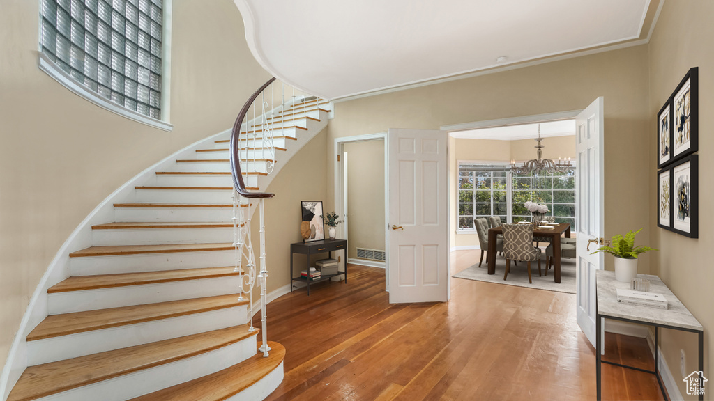 Staircase featuring a chandelier, wood-type flooring, and baseboards