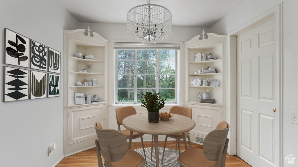 Dining space featuring built in shelves, a chandelier, and light wood-style floors