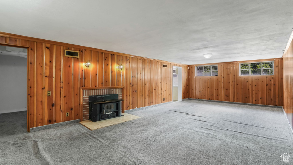 Unfurnished living room featuring carpet flooring and wooden walls