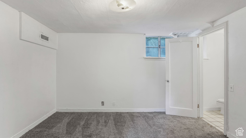 Basement with baseboards, carpet flooring, and a textured ceiling