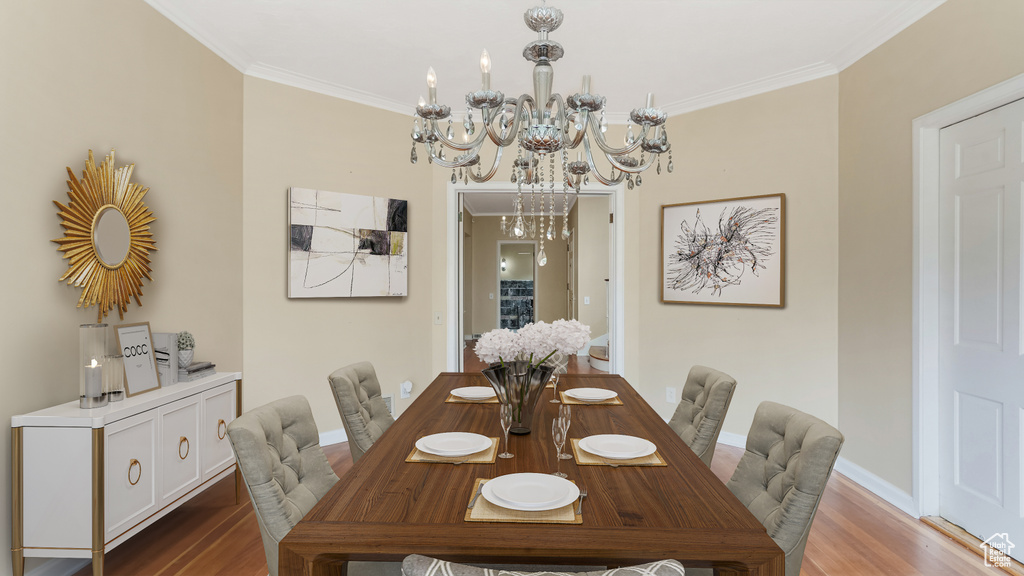 Dining room featuring a chandelier, wood finished floors, crown molding, and baseboards