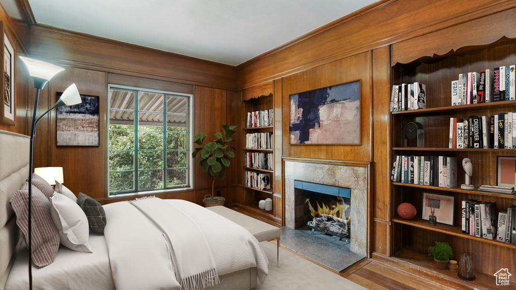Bedroom featuring wooden walls, a high end fireplace, and wood finished floors