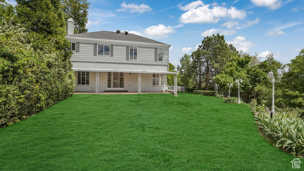 Rear view of property featuring a chimney, a patio, and a yard