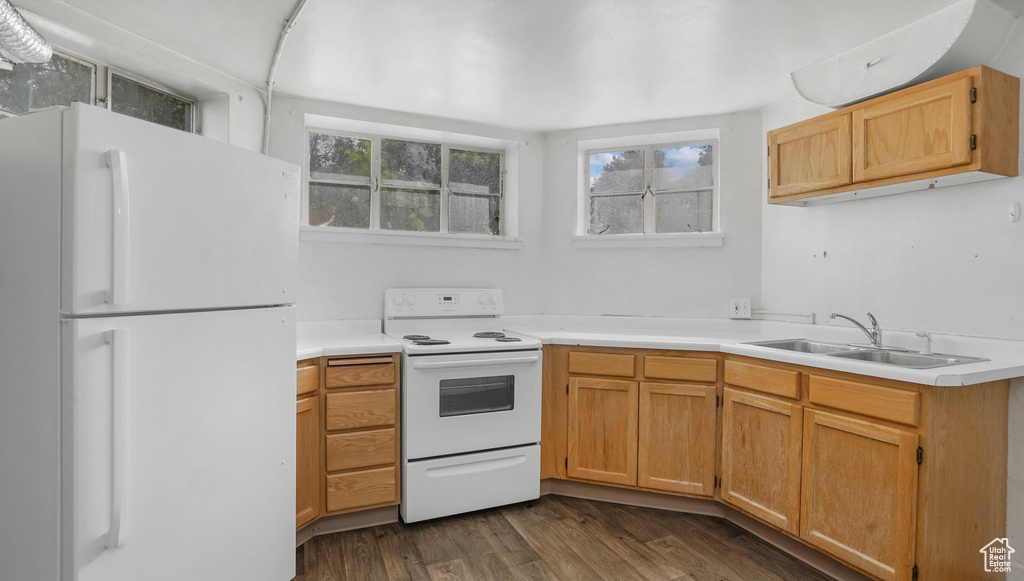 Kitchen featuring white appliances, a sink, light countertops, and dark wood finished floors