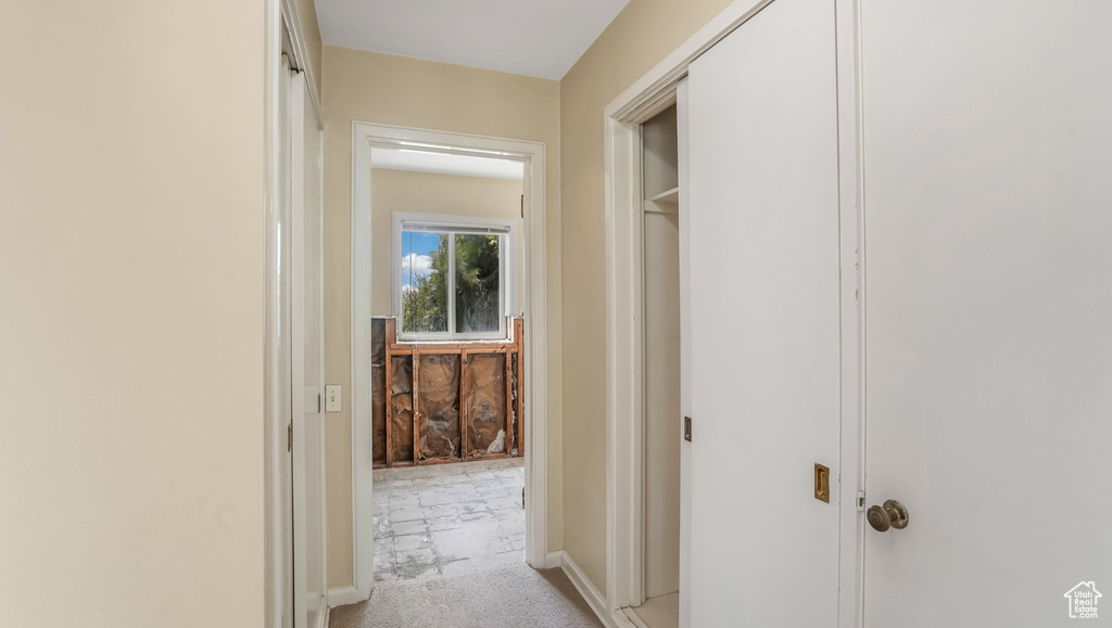 Hallway with light carpet and baseboards