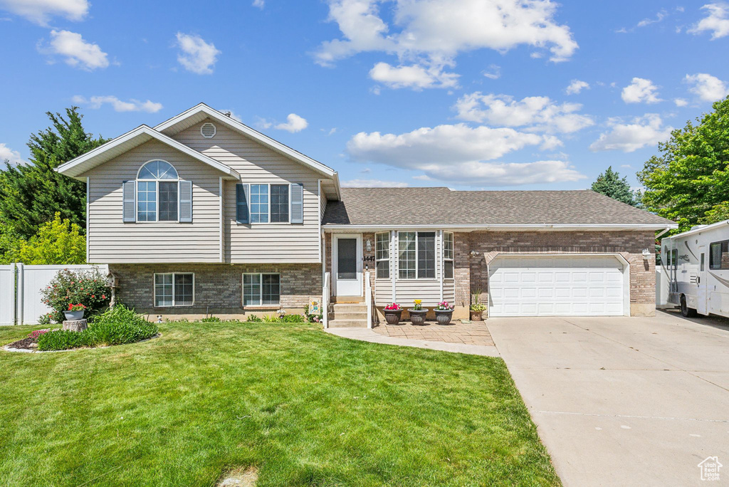 Split level home with entry steps, brick siding, a garage, and driveway