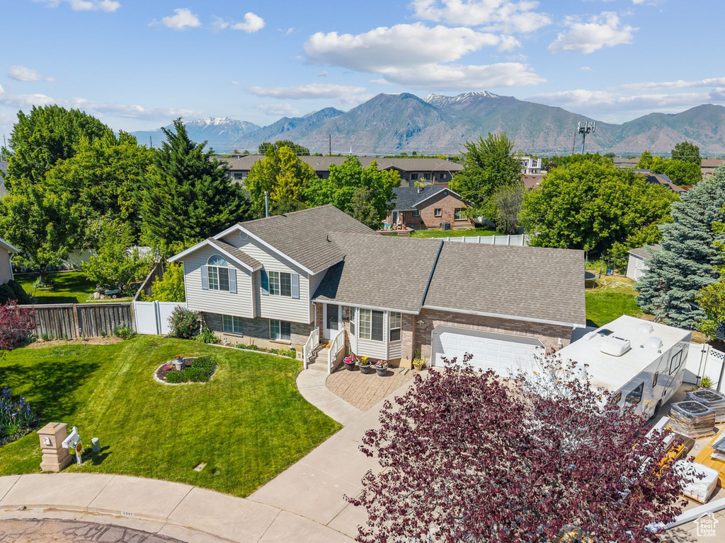 View of front of home with a garage, a mountain view, and roof with shingles