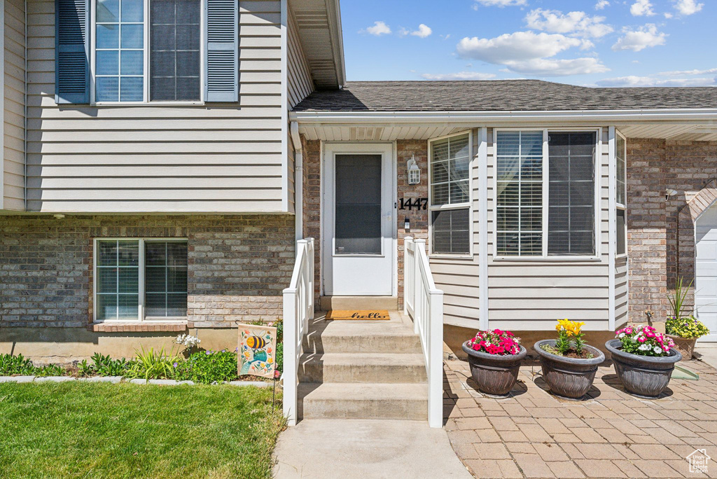 Entrance to property with brick siding and a shingled roof