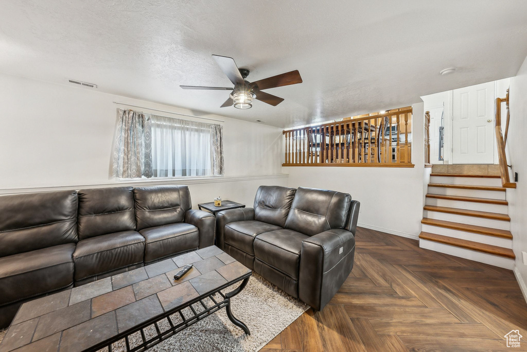 Living area with ceiling fan, stairs, and baseboards