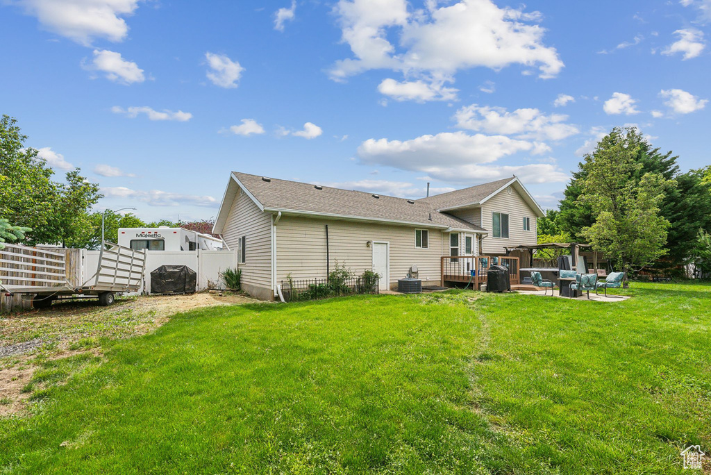 Back of property with a deck, central AC, and roof with shingles