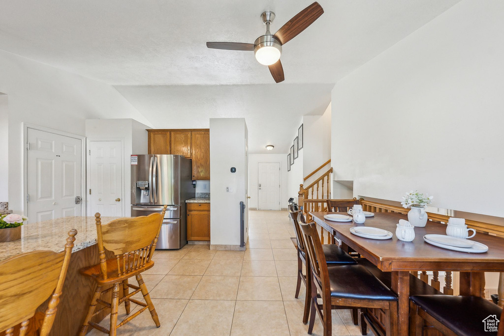 Dining space featuring ceiling fan, light tile patterned flooring, and stairs
