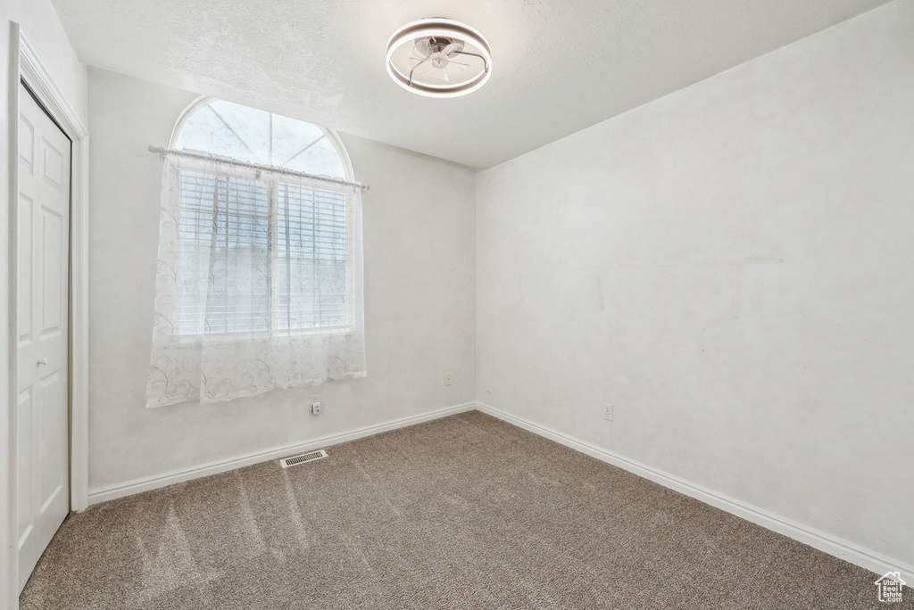 Carpeted empty room featuring baseboards and a textured ceiling