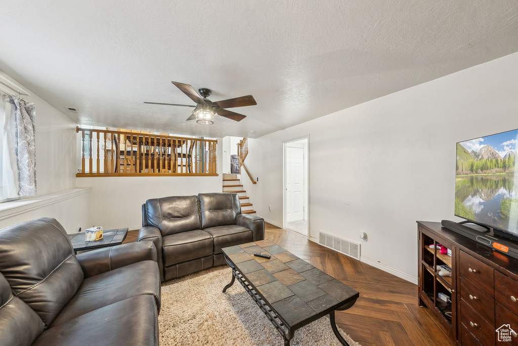 Living room featuring a ceiling fan, baseboards, and stairs