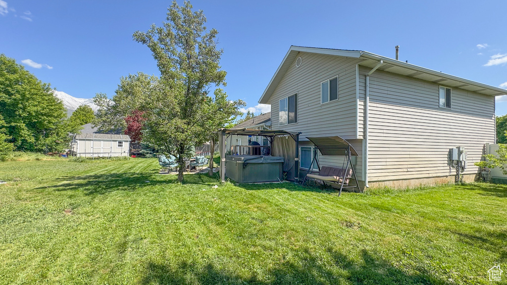 View of side of home featuring a hot tub and a yard