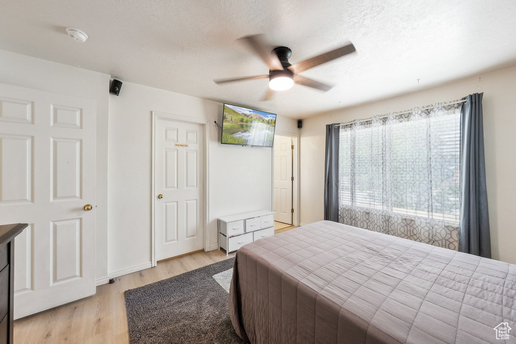 Bedroom with light wood-style floors, a textured ceiling, and a ceiling fan