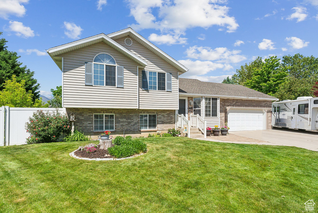 Tri-level home with an attached garage, brick siding, and driveway