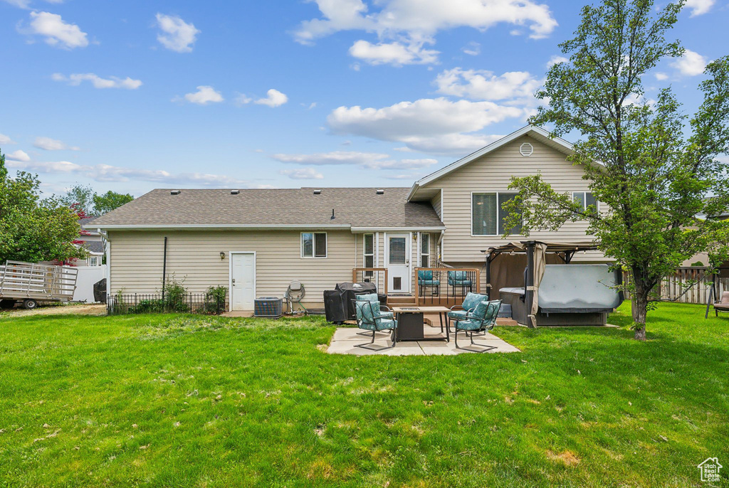 Back of property with a patio, a shingled roof, a fire pit, and cooling unit