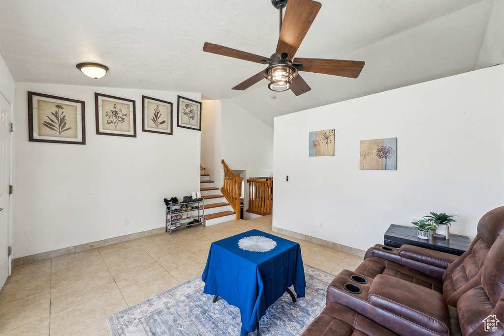 Sitting room featuring stairs, ceiling fan, vaulted ceiling, light tile patterned flooring, and baseboards
