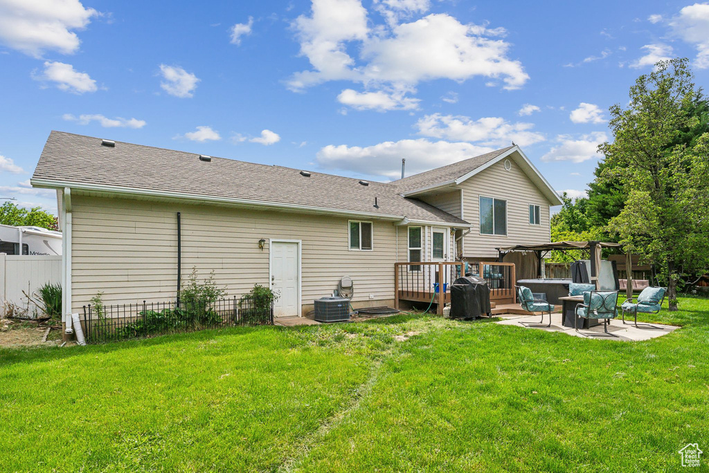 Rear view of property featuring a wooden deck, a patio area, central air condition unit, roof with shingles, and a pergola