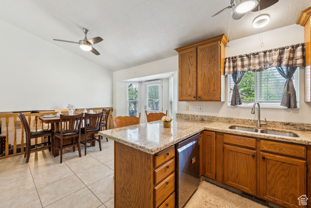 Kitchen featuring stainless steel dishwasher, a ceiling fan, a sink, lofted ceiling, and brown cabinets