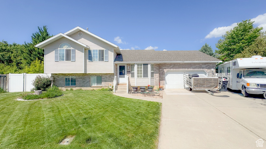 Tri-level home with driveway, a garage, and brick siding