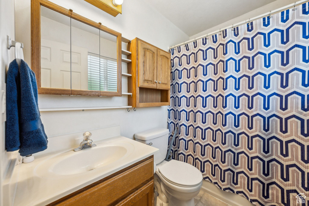 Bathroom featuring toilet, vanity, and a shower with curtain