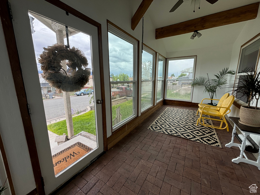 Sunroom featuring beamed ceiling and brick floors