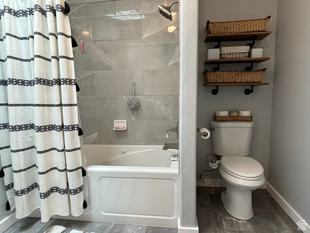 Bathroom with baseboards, toilet, and shower / bath combination with curtain
