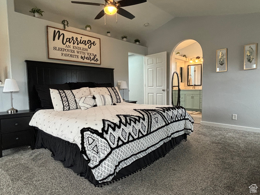 Bedroom with lofted ceiling, baseboards, carpet flooring, arched walkways, and ensuite bathroom