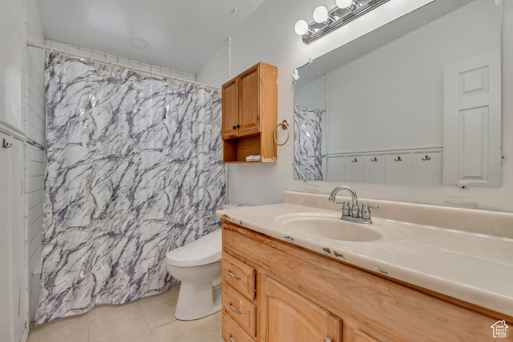 Bathroom with tile patterned floors, toilet, vanity, and a shower with curtain