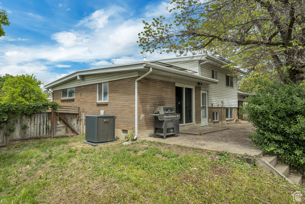 Rear view of property featuring central AC unit, brick siding, and a patio