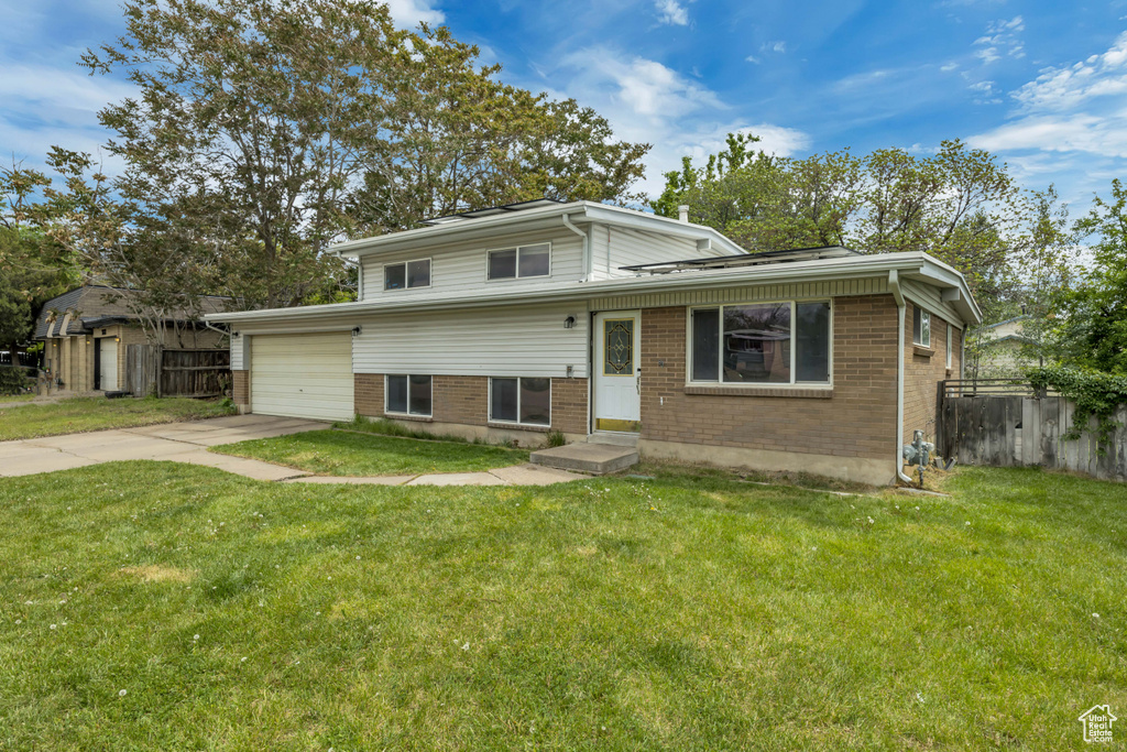 Split level home featuring brick siding, concrete driveway, a garage, and entry steps