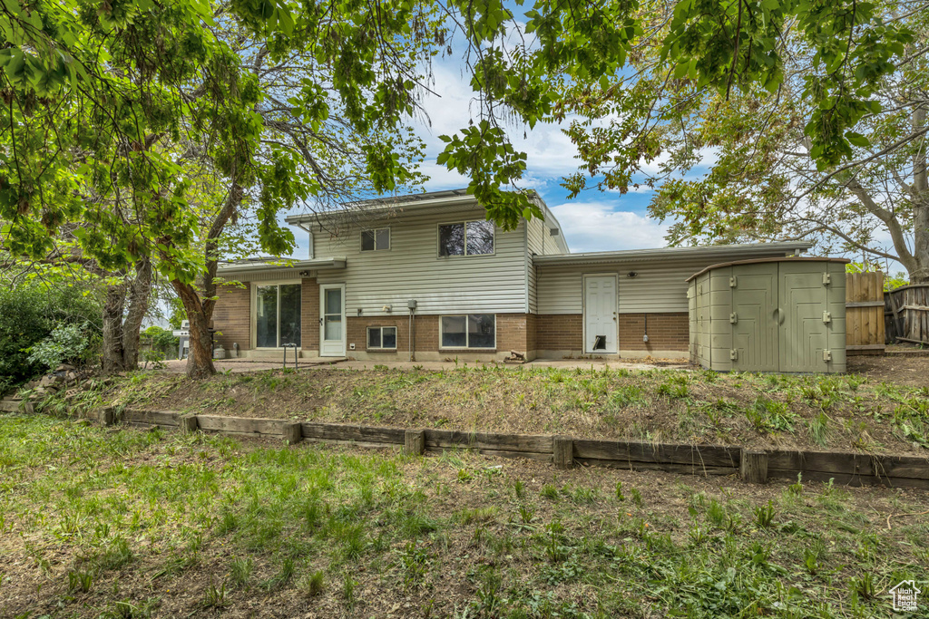 Back of property with brick siding, fence, and a shed