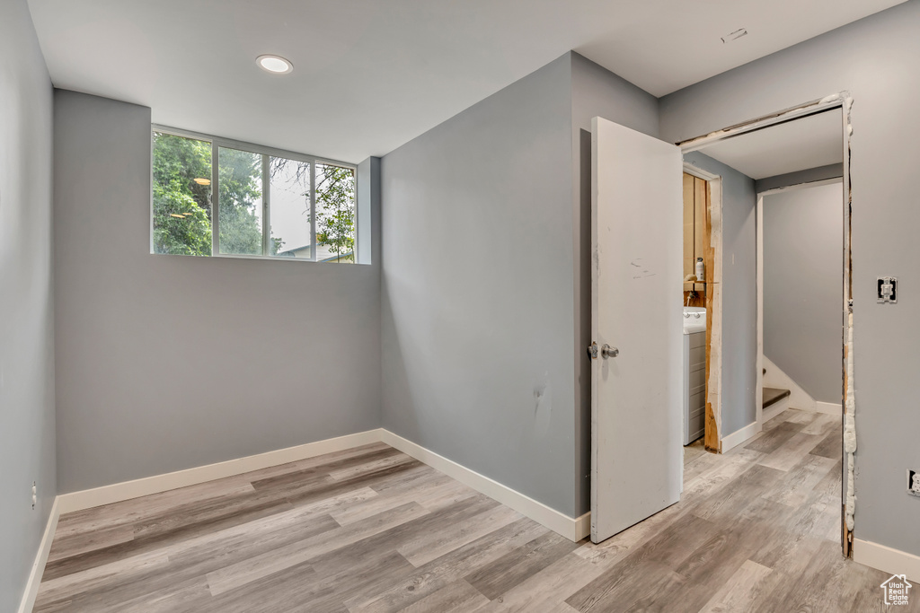 Empty room with wood finished floors, baseboards, recessed lighting, washer / clothes dryer, and stairway
