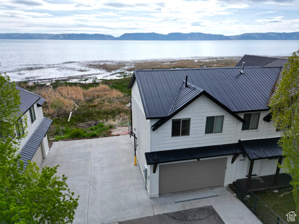View of front of property featuring metal roof, a garage, and a water and mountain view