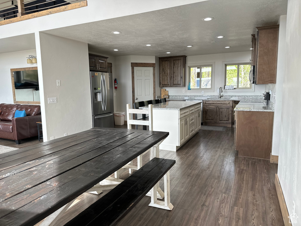 Kitchen featuring stainless steel appliances, a sink, a center island, recessed lighting, and dark wood-style flooring