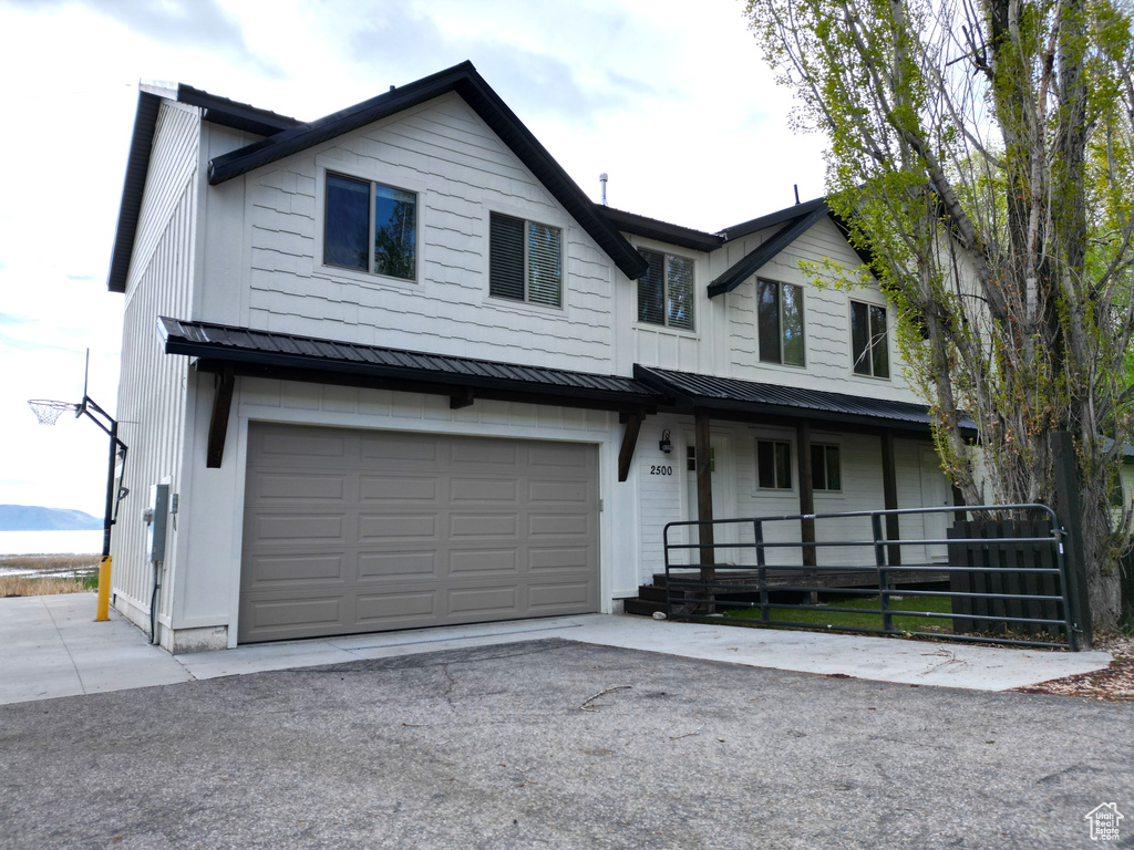 View of front facade featuring a porch, a standing seam roof, metal roof, an attached garage, and concrete driveway