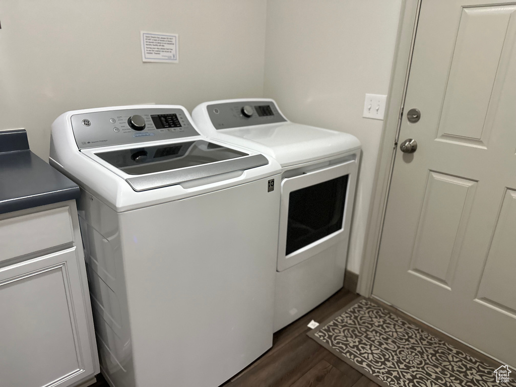 Washroom featuring separate washer and dryer, dark wood finished floors, and cabinet space